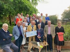 Club member and guests gather around as Joint-President Ray Webber presents Geraldine with a donation to Guide Dogs for the Blind.